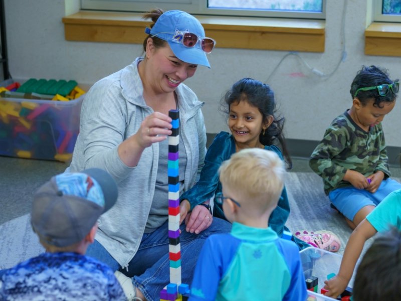 preschool teacher stacking colorful blocks with young students