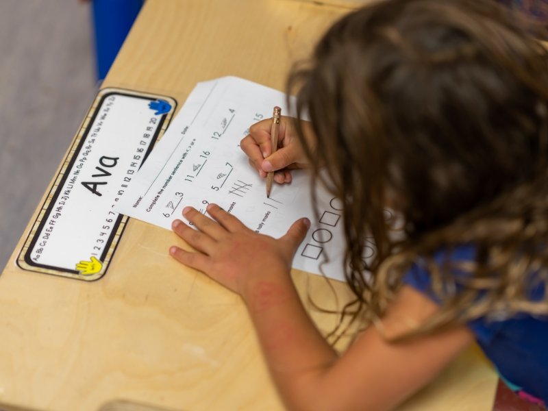 young student practicing writing and math