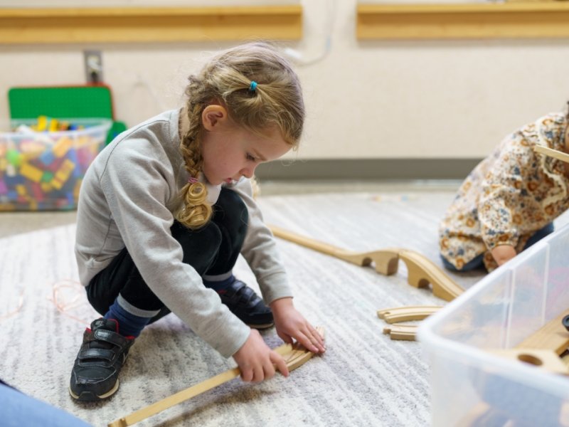 student building with wooden toy train tracks