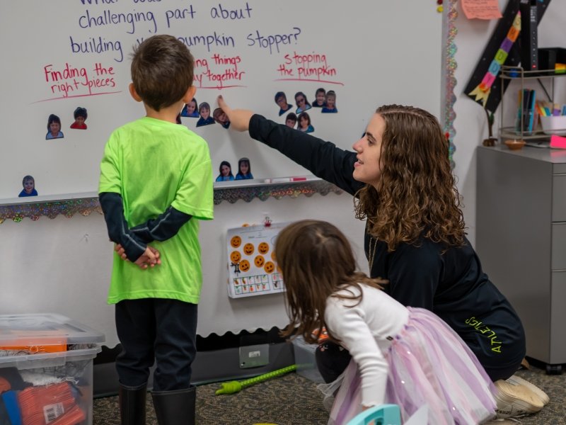 teacher and 2 students working at the whiteboard