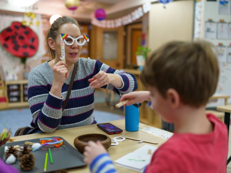 young student and teacher making popsicle stick masks