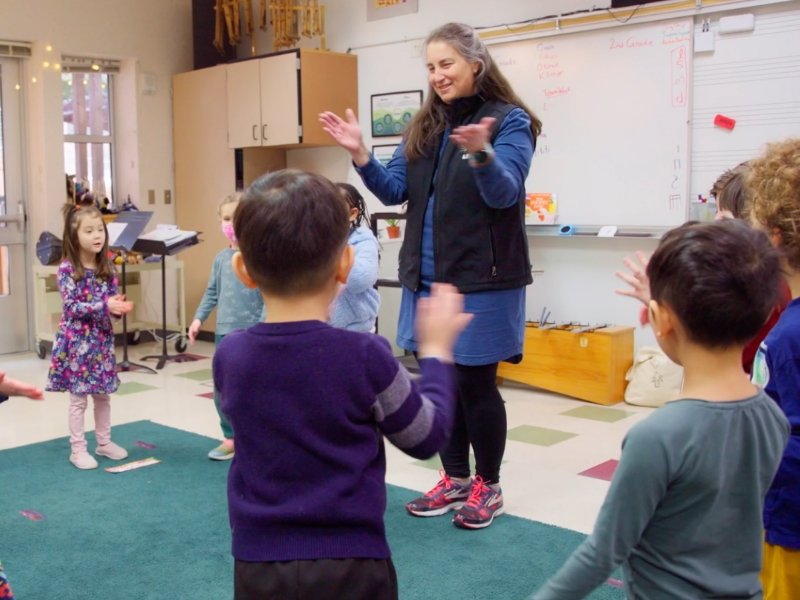 students in music class dancing and singing led by the teacher