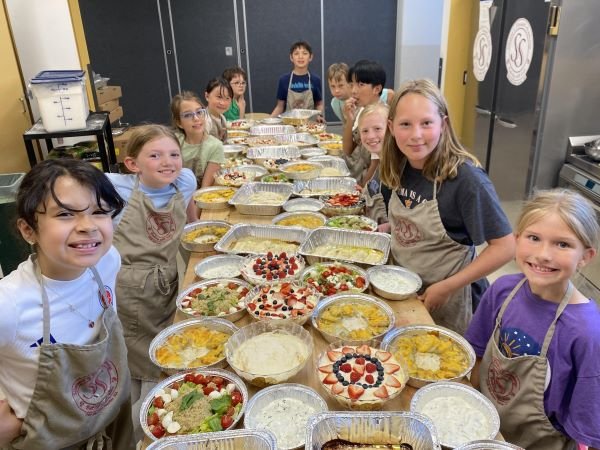 Students at a long table showing off their finished three-course meal as part of a cooking class