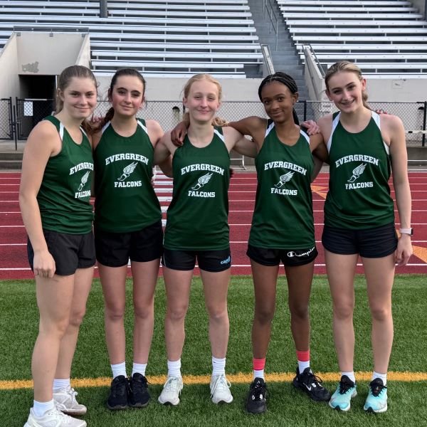 Middle school girls track team posing on the track with arms around each other's shoulders
