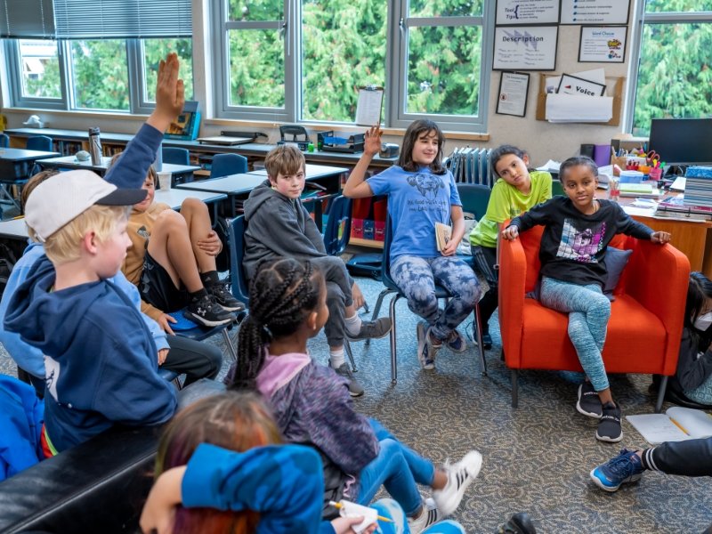 students in a group with hands raised