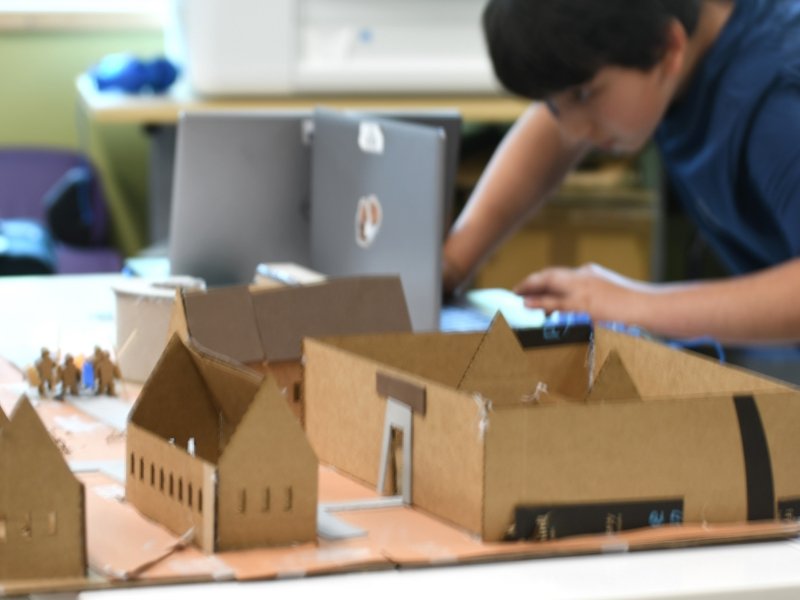 student focused on building model structures from cardboard