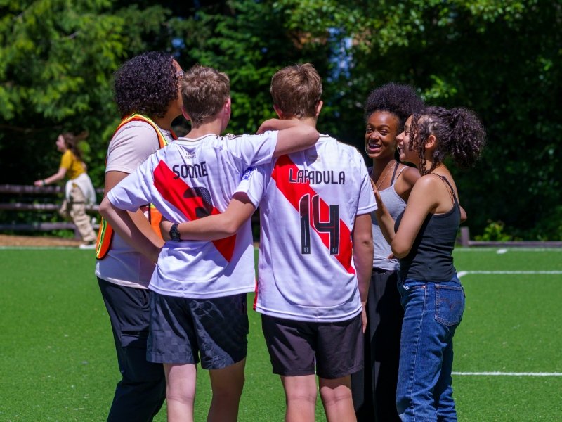Group of students huddled on athletic field on a sunny day
