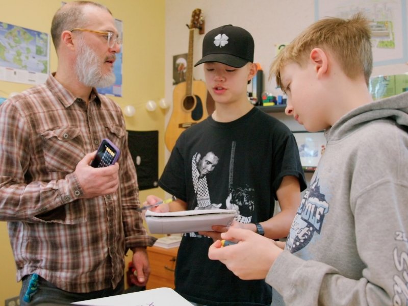 teacher and middle school students discussing during math class