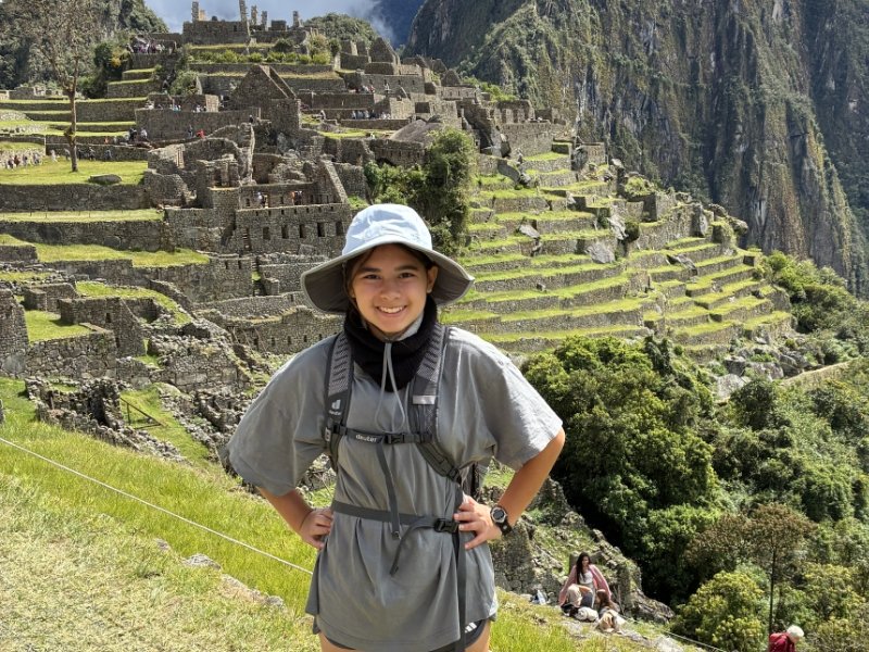 student standing in front of Machu Pichu, smiling, wearing hiking gear
