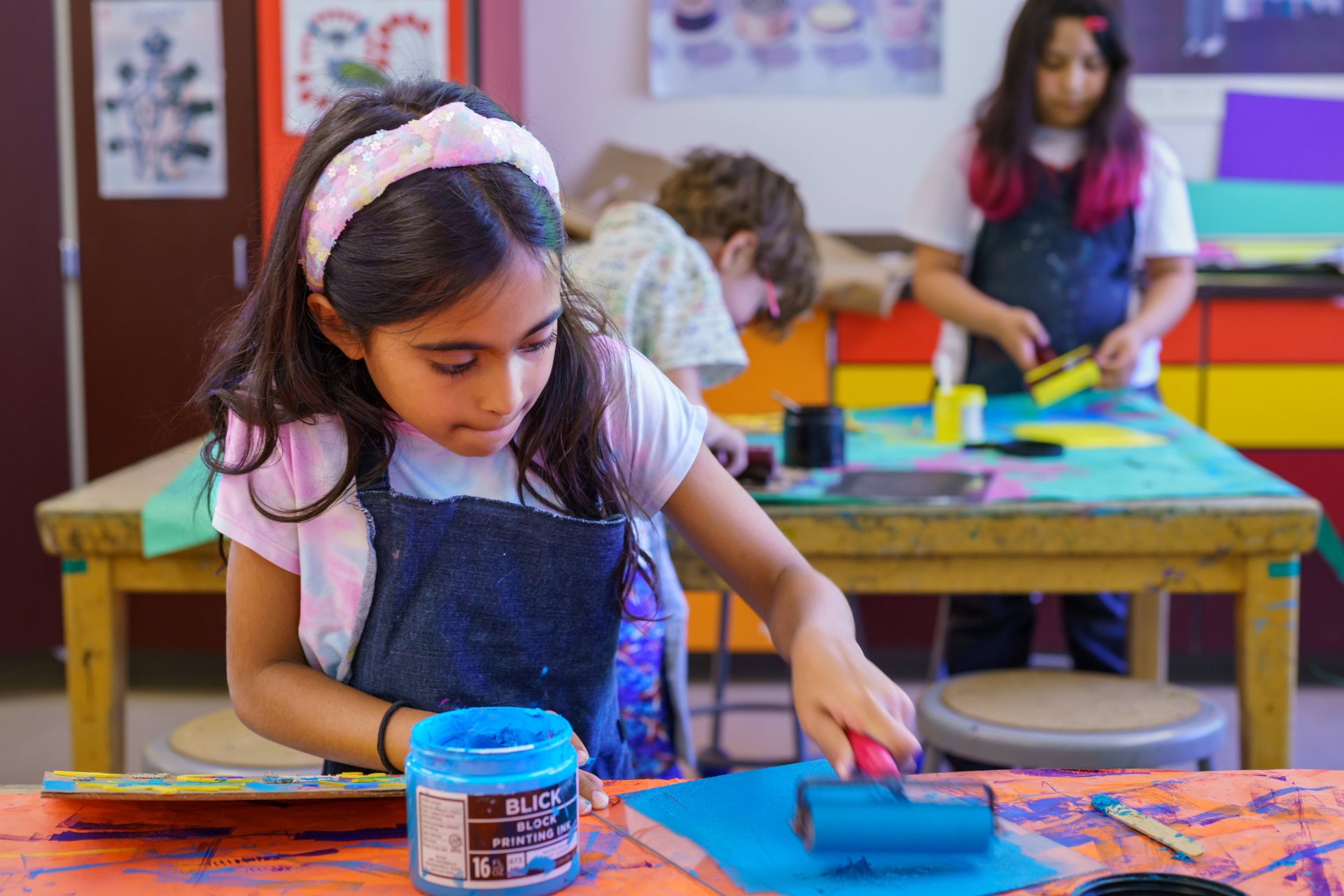 student focused on rolling ink onto paper as part of a project