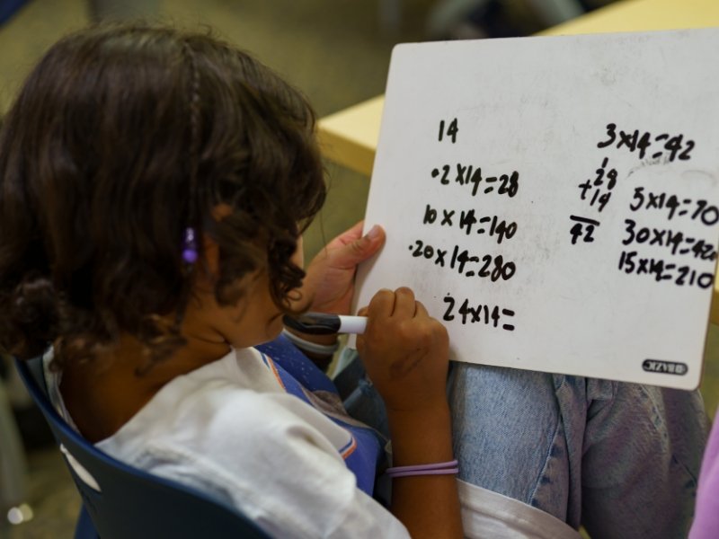student working on math equations on a small whiteboard