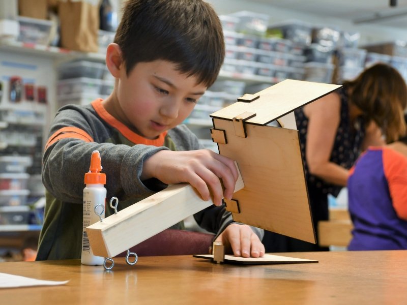 young student building a model with glue and cardboard in the makerspace