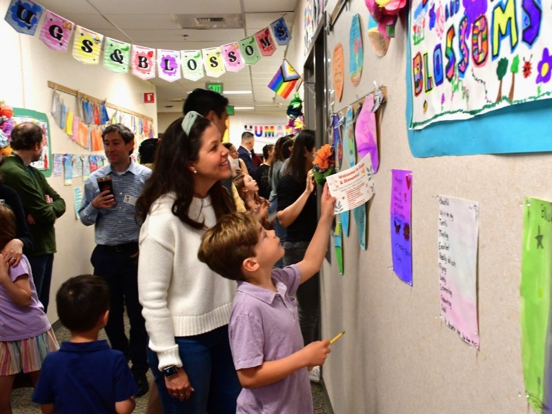 students showing parents and guardians their artwork displayed in the hallway