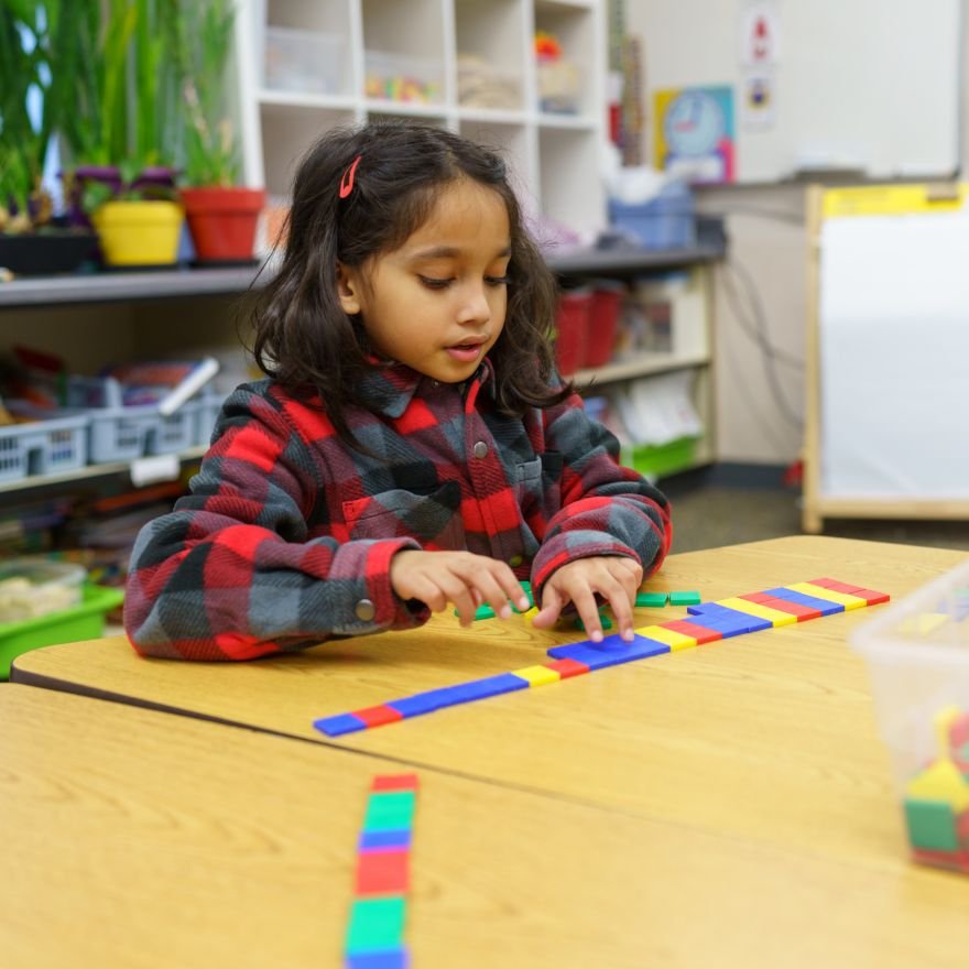 young student looking focused manipulating colored shapes