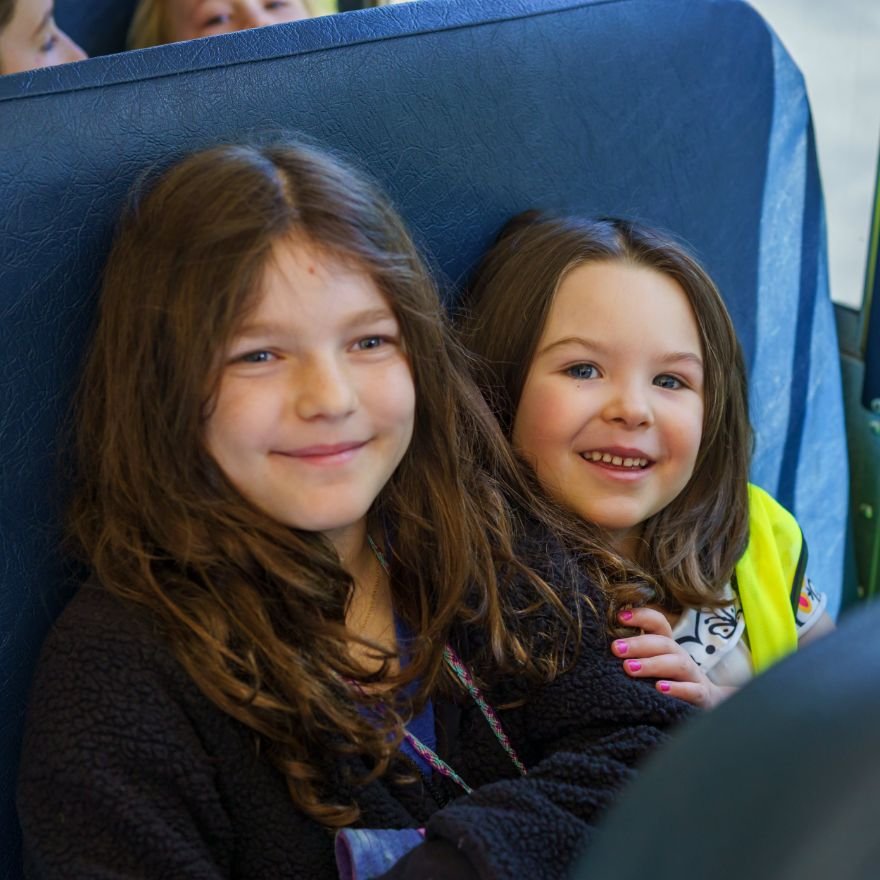 an older and a younger student enjoying sitting together on a school bus