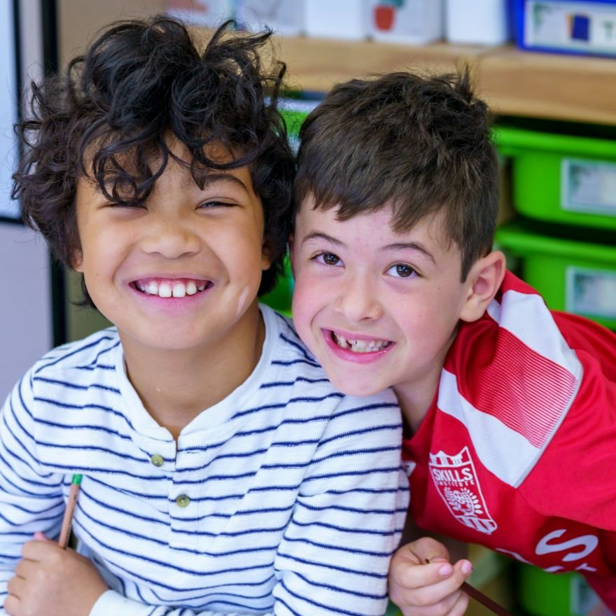 two young students laughing and smiling together, one with a missing tooth