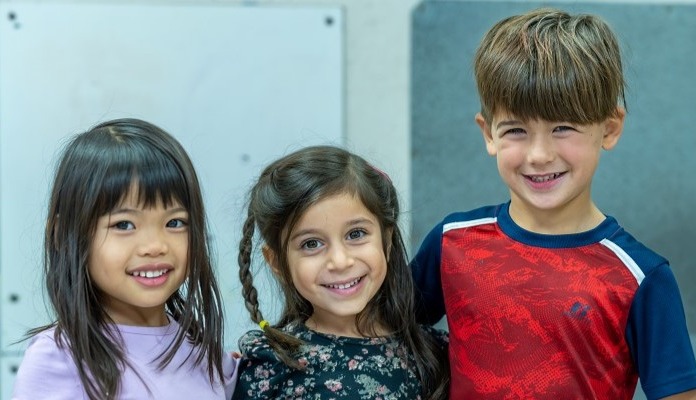 three young children standing and smiling together